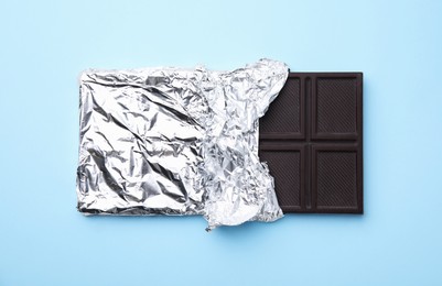 Photo of Tasty chocolate bar on light blue background, top view