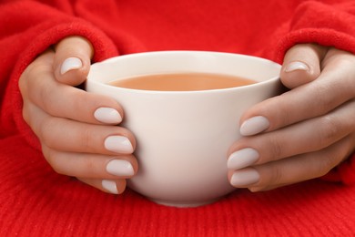 Photo of Woman with white polish on nails holding cup of hot drink, closeup