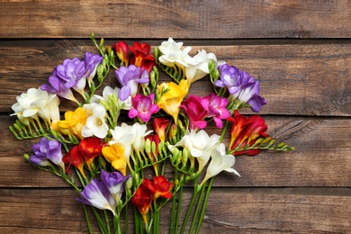 Photo of Beautiful freesia flowers on wooden background