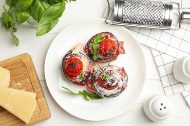 Photo of Baked eggplant with tomatoes, cheese and basil served on white wooden table, flat lay