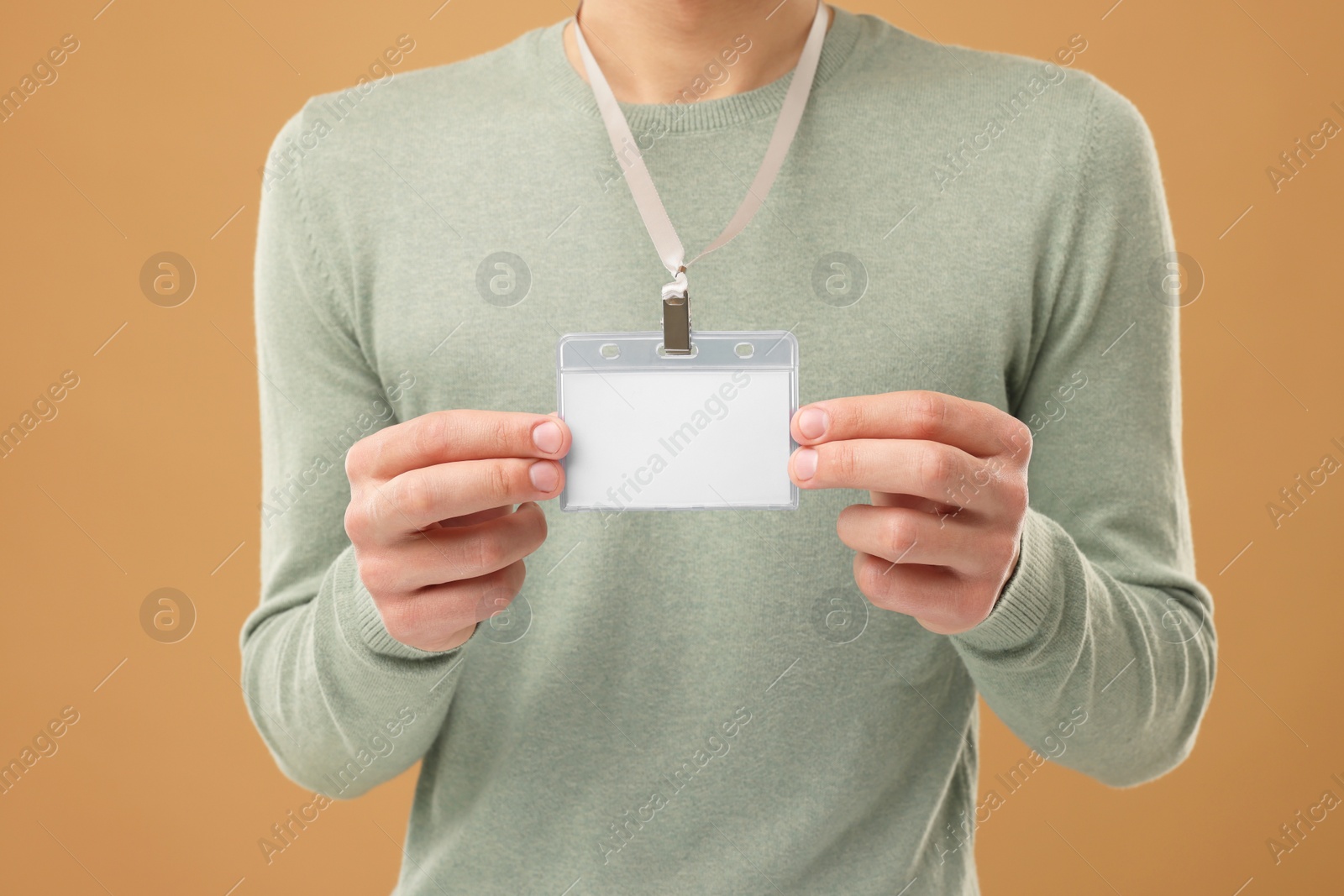 Photo of Man with blank badge on light brown background, closeup