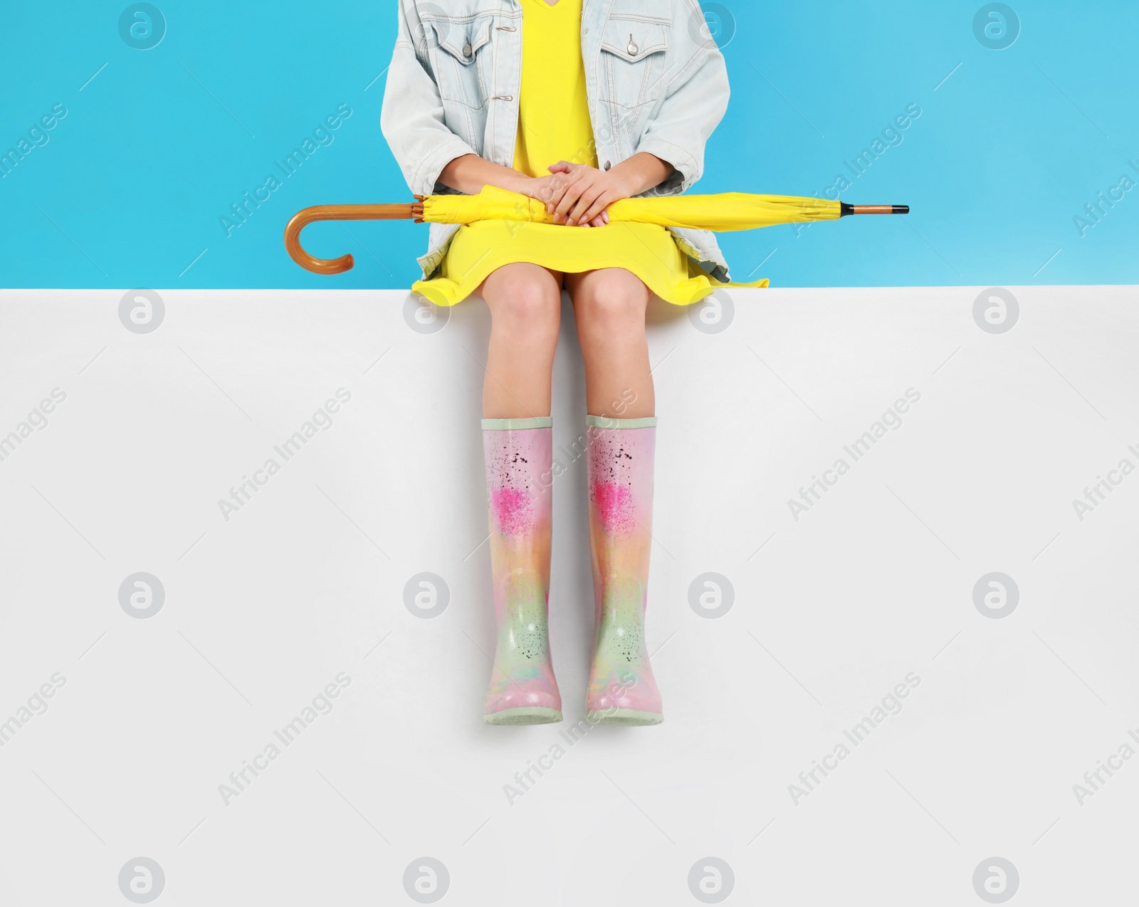 Photo of Woman wearing gumboots on color background, closeup. Stylish rubber shoes