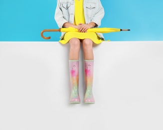 Photo of Woman wearing gumboots on color background, closeup. Stylish rubber shoes