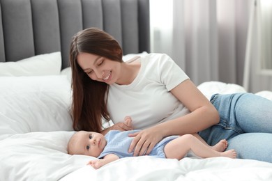 Photo of Mother with her cute baby on bed indoors