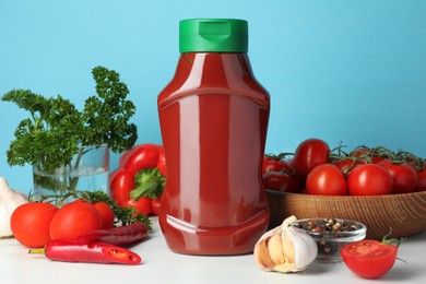 Photo of Bottle of tasty ketchup and ingredients on white marble table