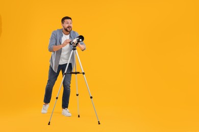 Photo of Happy astronomer with telescope on orange background. Space for text