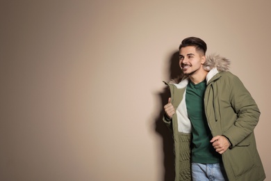 Photo of Young man wearing warm clothes on color background, space for text. Ready for winter vacation