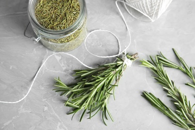 Photo of Flat lay composition with dried rosemary in jar and fresh twigs on grey table
