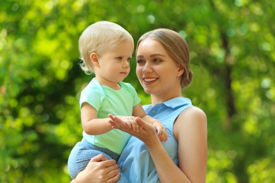 Photo of Young mother with her cute child in green park