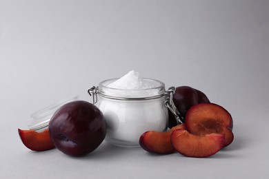 Photo of Jar with sweet fructose powder and ripe plums on white background