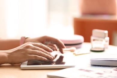 Photo of Female blogger using tablet at table indoors