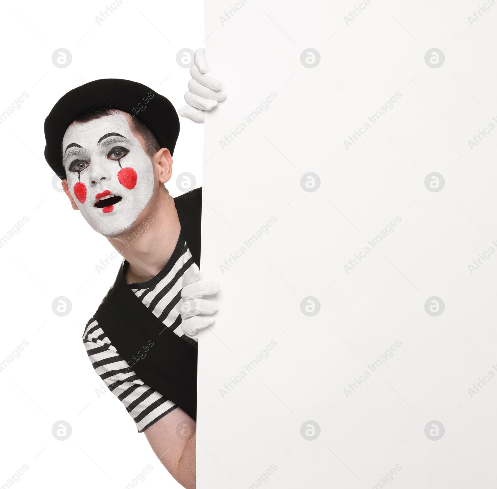 Photo of Funny mime artist peeking out of blank poster on white background