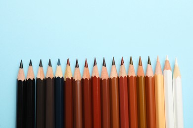Photo of Colorful pencils on light blue background, flat lay with space for text. Stop racism