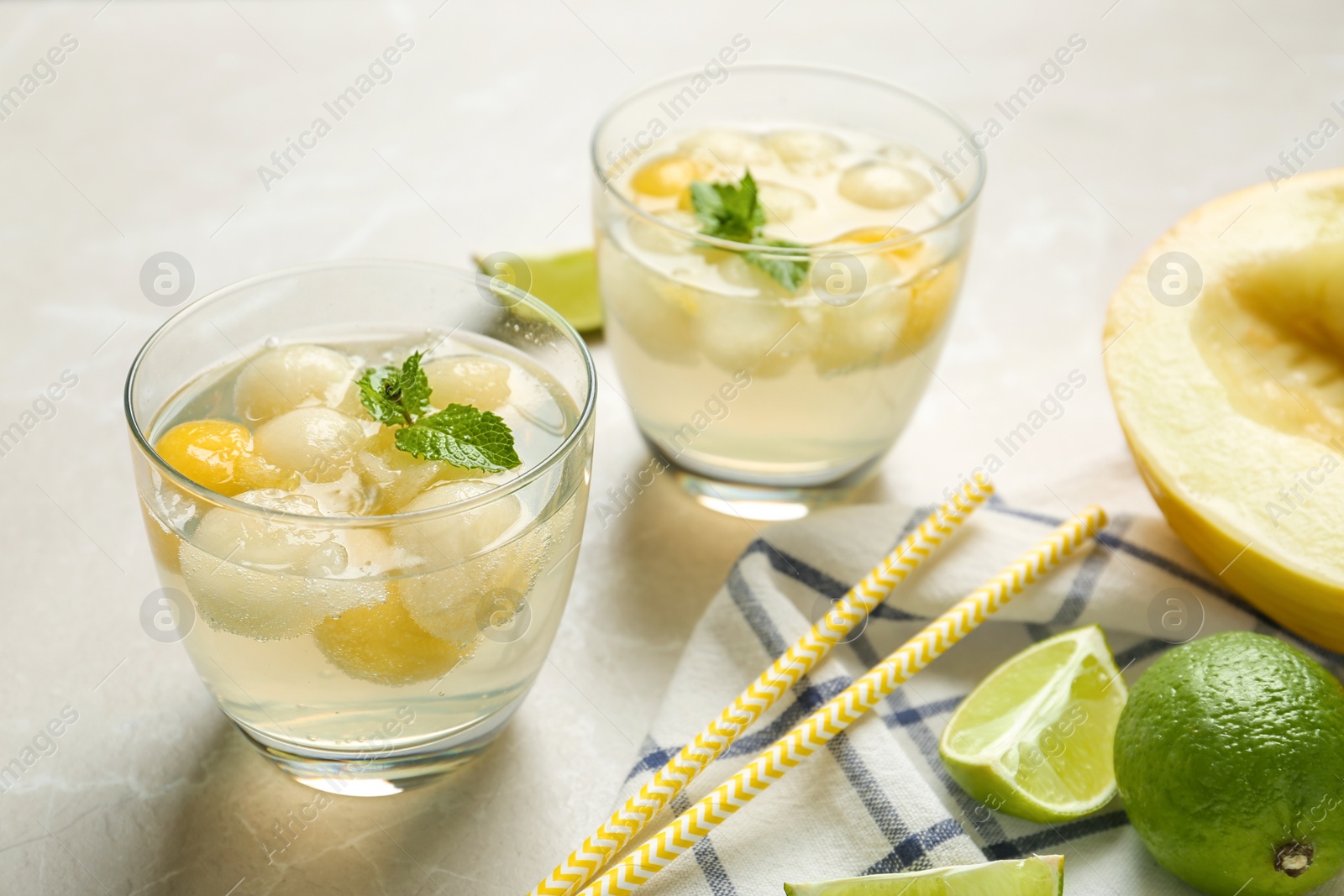 Photo of Glasses of melon ball cocktail with mint on light grey marble table