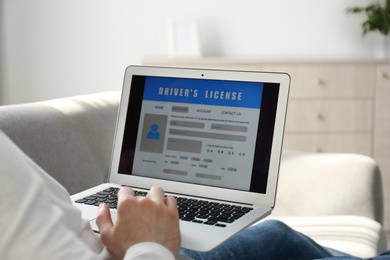 Photo of Man using laptop to fill driver's license application form at home, closeup