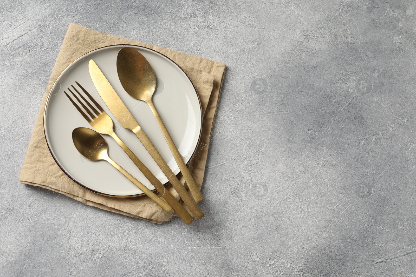 Stylish cutlery, plate and napkin on light grey table, top view. Space for text Photo of Stylish cutlery, plate and napkin on light grey table, top view. Space for text