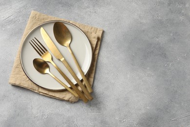 Photo of Stylish cutlery, plate and napkin on light grey table, top view. Space for text