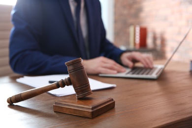 Photo of Notary working with laptop at table, focus on gavel. Law and justice concept