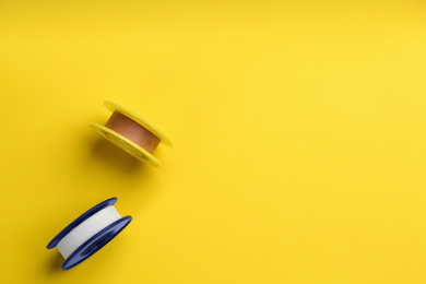 Photo of Sticking plaster rolls on yellow background, top view. Space for text