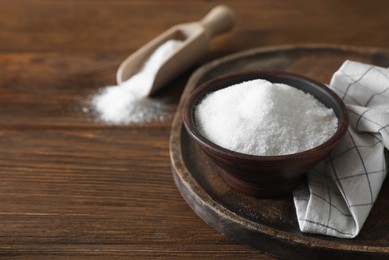Photo of Organic salt in bowl on wooden table, closeup. Space for text