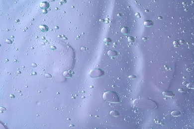 Photo of Transparent cleansing gel on violet background, top view. Cosmetic product