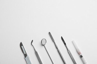 Photo of Set of different dentist's tools and syringe on light background, flat lay. Space for text