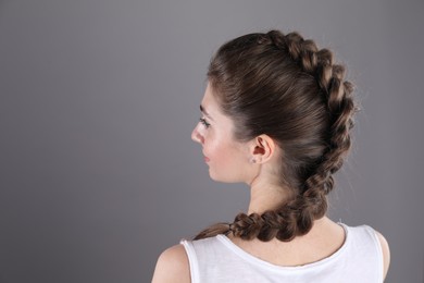 Photo of Woman with braided hair on grey background, back view. Space for text