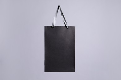 Photo of One black paper shopping bag on grey background