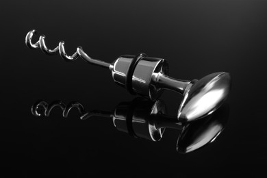 Photo of One metal corkscrew on dark mirror surface, closeup