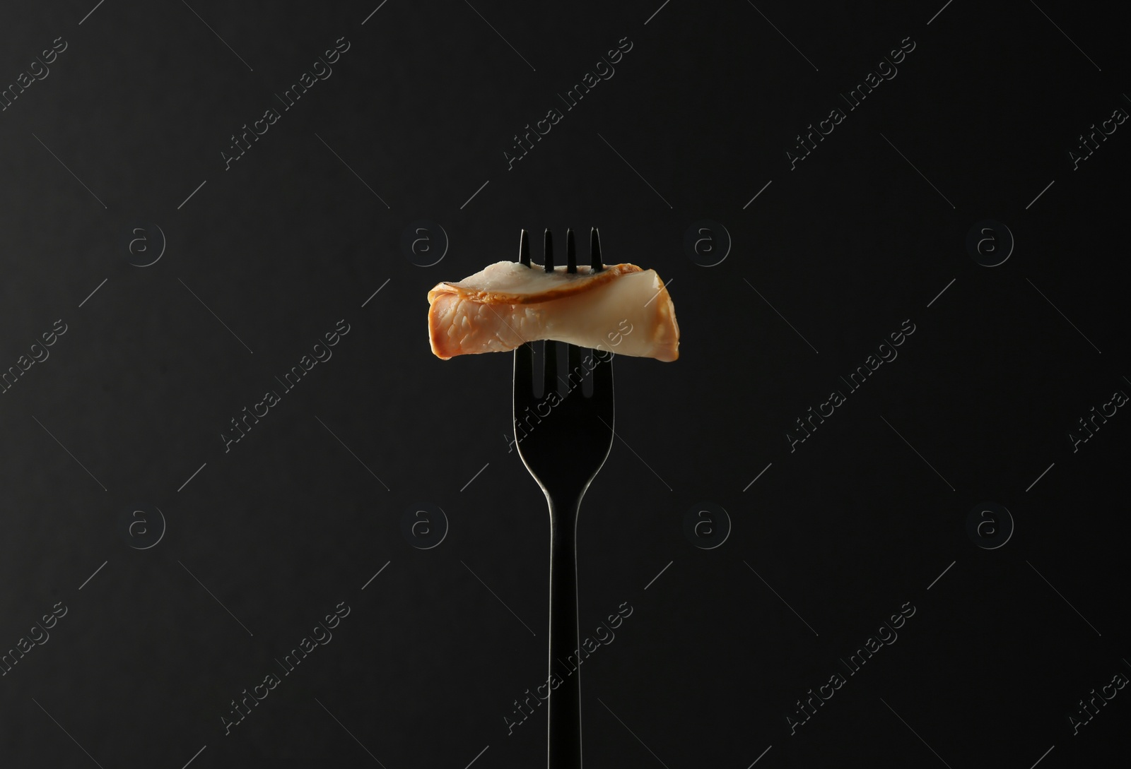 Photo of Fork with slice of ham on black background