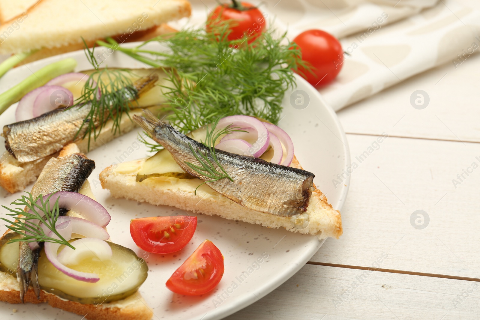 Delicious sandwiches with sprats, pickled cucumber, onion and dill served on white wooden table, closeup Photo of Delicious sandwiches with sprats, pickled cucumber, onion and dill served on white wooden table, closeup