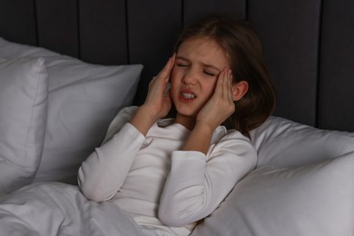Photo of Little girl suffering from headache in bed at night