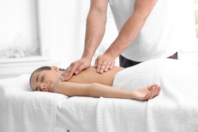 Photo of Relaxed woman receiving back massage in wellness center