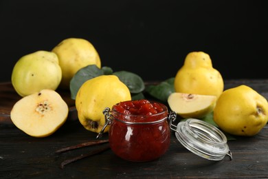 Photo of Delicious quince jam and fruits on black wooden table