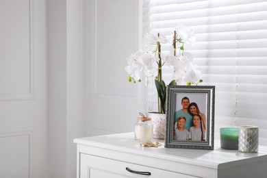 Photo of Framed family photo and orchid flower on drawer indoors, space for text