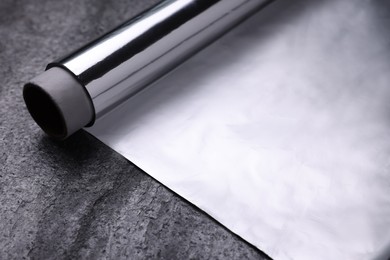Photo of Roll of aluminum foil on grey table, closeup