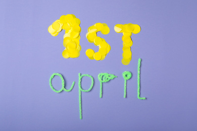 Photo of Phrase 1st APRIL on lilac background, flat lay. Fool's Day