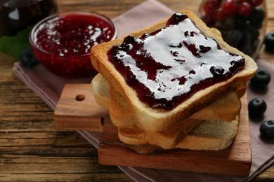 Photo of Delicious toasts with jam served on wooden table, closeup