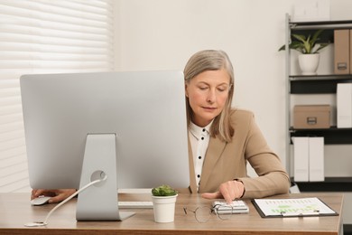 Photo of Senior accountant working at wooden desk in office