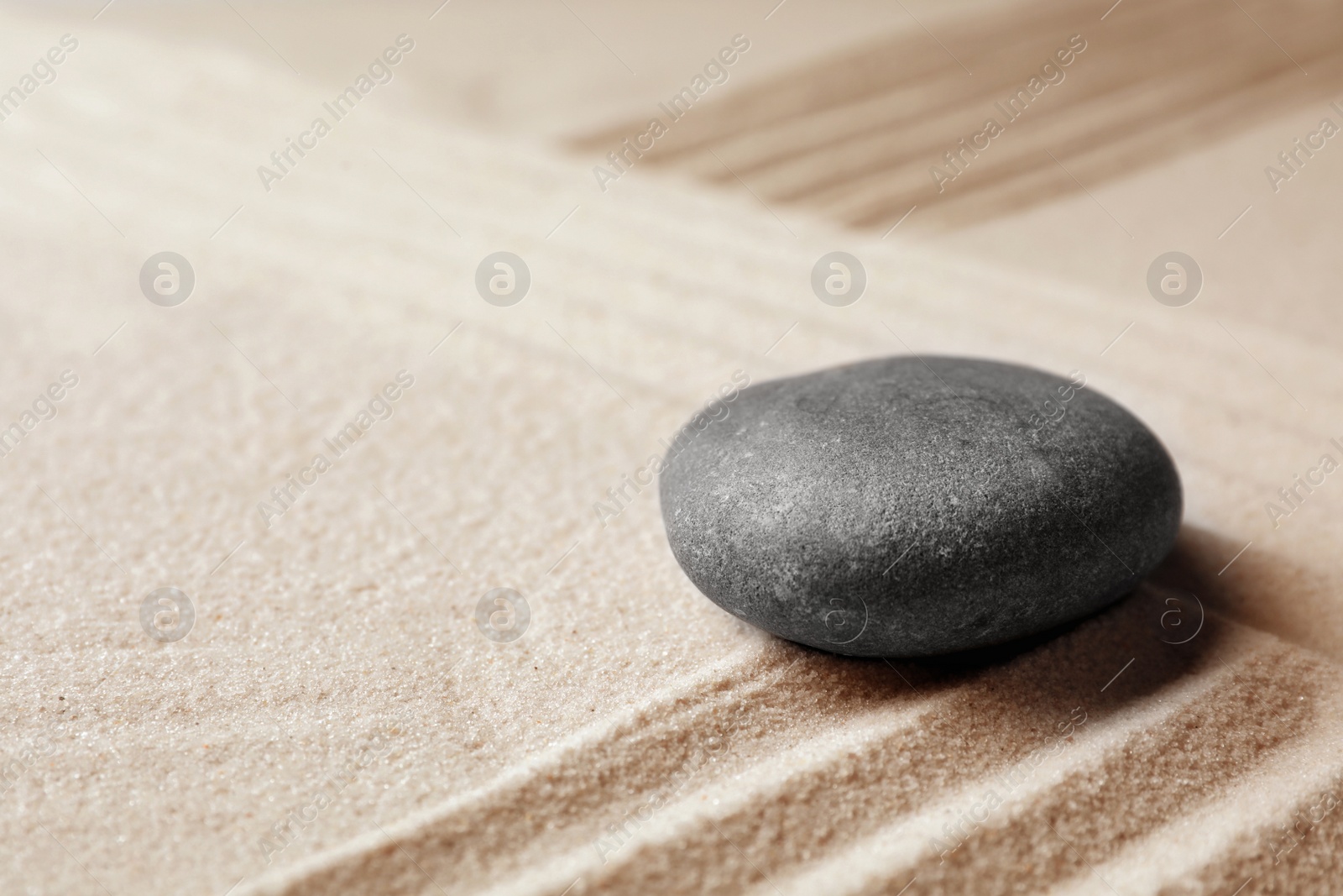 Photo of Zen garden stone on sand with pattern, space for text. Meditation and harmony