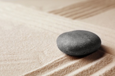 Photo of Zen garden stone on sand with pattern, space for text. Meditation and harmony