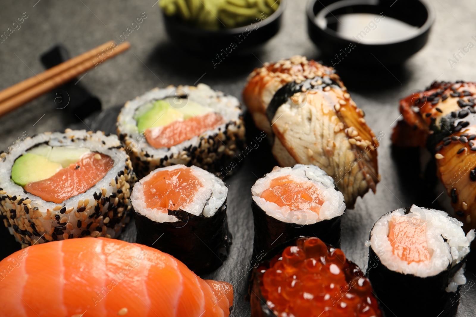 Photo of Set of delicious sushi rolls on slate board, closeup