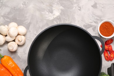 Wok and different products on grey textured table, flat lay. Space for text