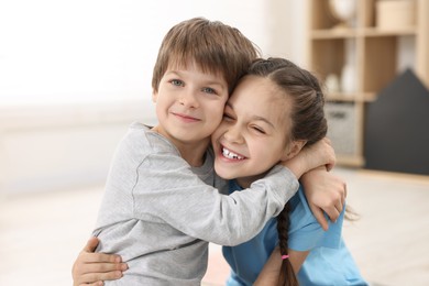 Happy brother and sister hugging together at home