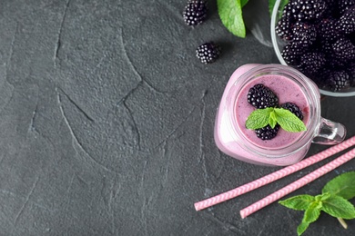 Flat lay composition with jar of delicious blackberry smoothie on black table. Space for text