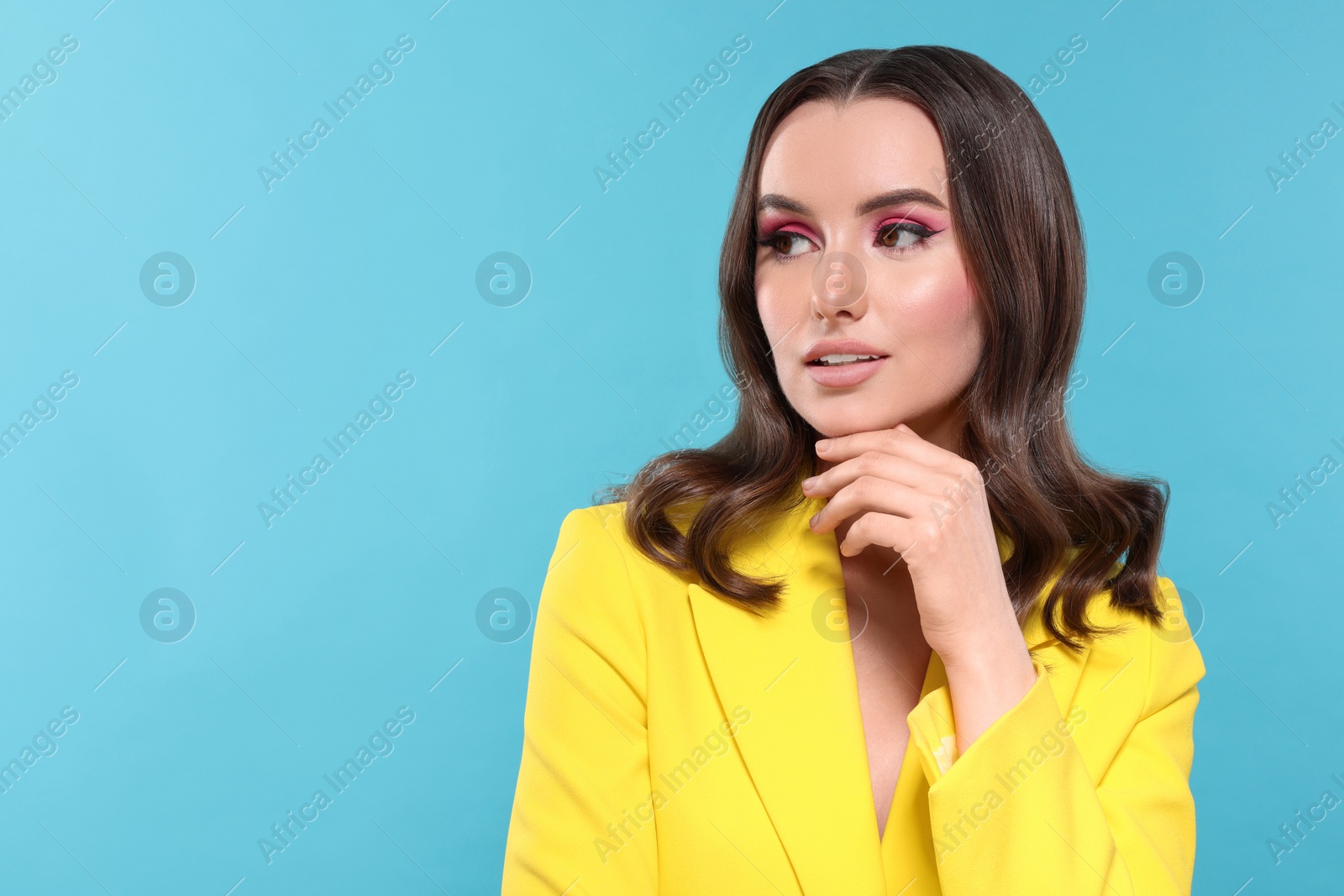 Photo of Portrait of beautiful young woman with makeup and gorgeous hair styling on light blue background. Space for text