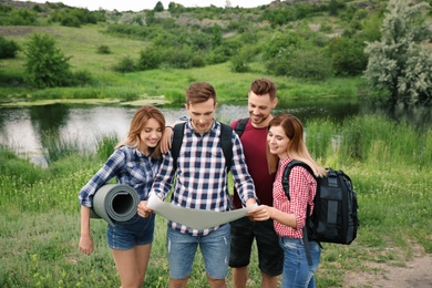 Photo of Group of young people exploring map in wilderness. Camping season