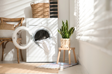 Photo of Modern washing machine in laundry room interior