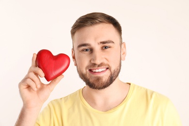 Photo of Young man holding wooden heart on white background