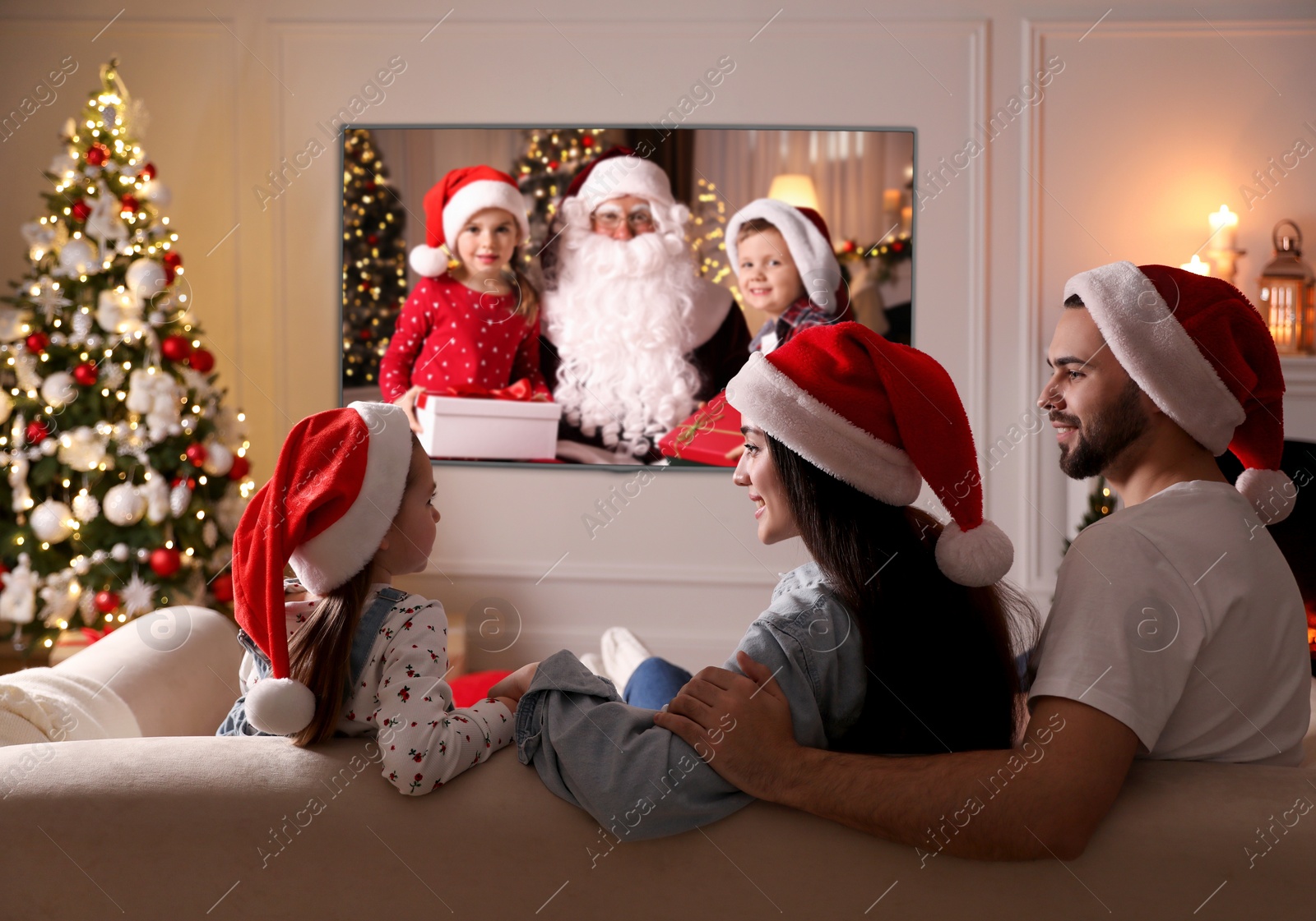 Image of Family watching TV movie in room decorated for Christmas